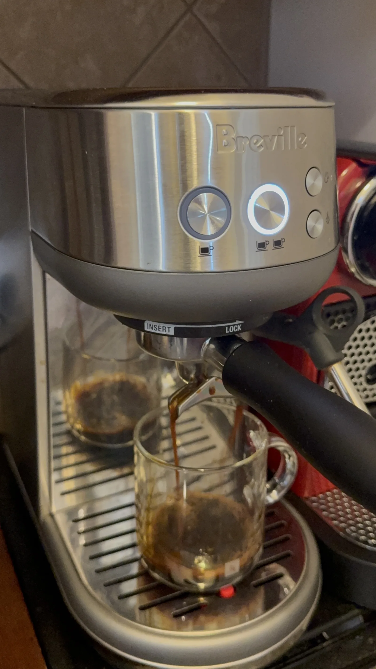 Espresso pouring from a Breville machine into a clear glass mug