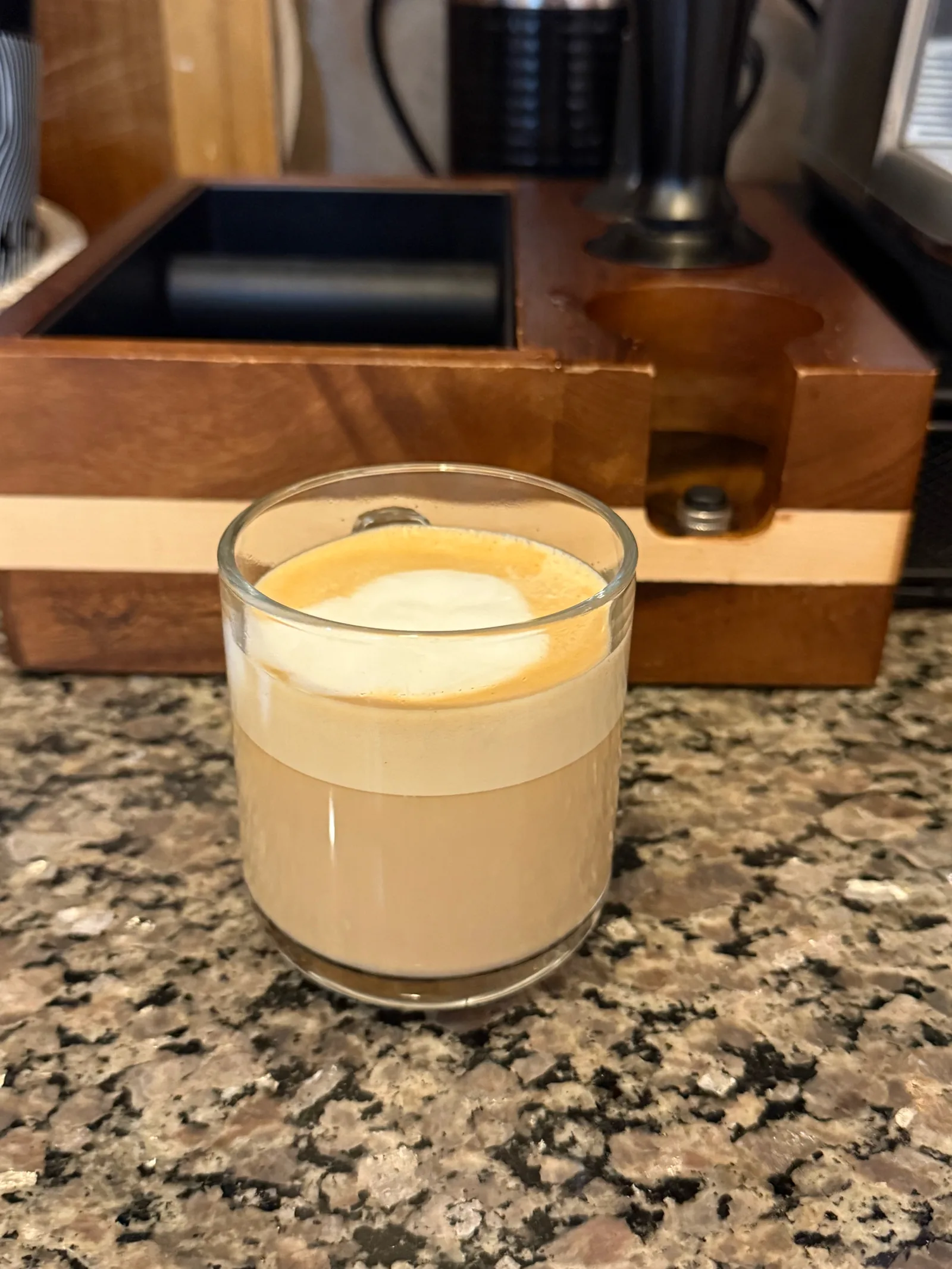 Finished milk drink in a small clear glass on a granite counter