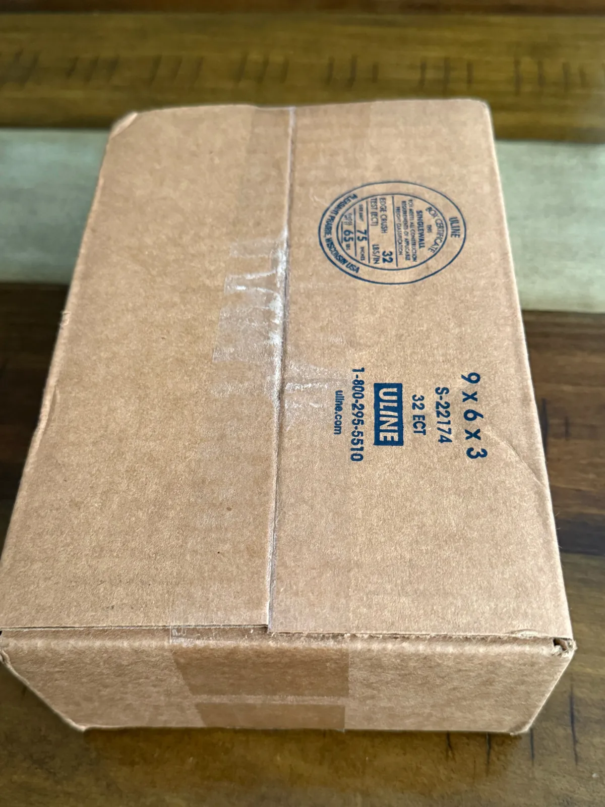 Plain brown Uline shipping box with no Volcanica branding, on a wooden table